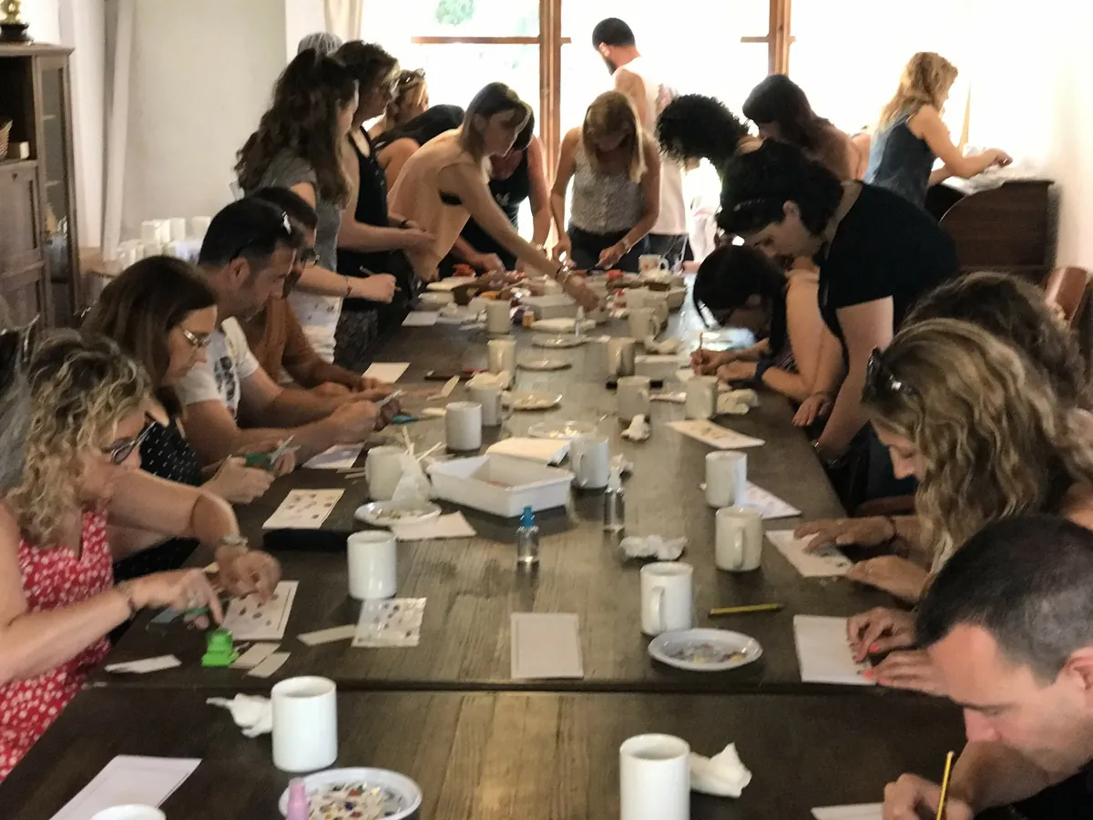 Un grup pintant ceràmica al voltant d'una taula llarga